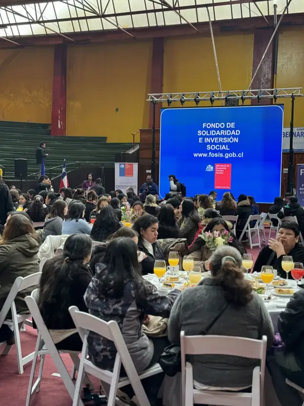 Evento institucional con pantalla LED y público en mesas