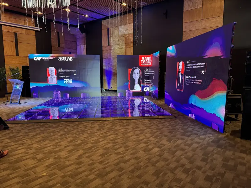 Foro con tres pantallas LED y podio en salón de eventos